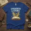 T-shirt with "Unearth A Story" text and a mole character reading a book, surrounded by mystical elements