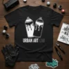 Black t-shirt with "Urban Art Lab" text and two white and black spray paint cans graphic