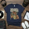 VelociRapper text above a muscular cartoon Velociraptor with sunglasses and gold chains holding a microphone, on a navy blue t-shirt