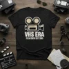 VHS Era Film Crew Est. 1985 text with retro video camera graphic on a black t-shirt