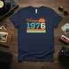 Vintage 1976 text graphic with retro sunset design on a navy blue t-shirt