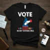 Black t-shirt with white text "VOTE IN MY VOTING ERA" and graphic of Statue of Liberty with hand casting ballot