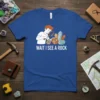 Wait I See A Rock t-shirt design featuring a person with a magnifying glass examining crystals and rocks