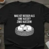 WAS IST BESSER ALS EINE KATZE? ZWEI KATZEN! text with two sleeping cats in a basket graphic on a black