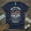 Navy t-shirt with "WE PAY MORE JUNK CARS BREVARD" text and graphics of cars being towed, advertising junk car buying