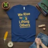 Blue t-shirt with yellow text "We Rise by Lifting Others" and graphic of two people lifting each other