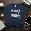 Weary student studying late at night graphic tee with text "WEARY" and illustration of books, lamp, and fallen coffee cup