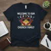 Welcome To Our Church Family text with heart hands, church, and dove graphic on a navy t-shirt
