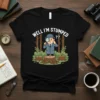 Well I'm Stumped?? text on a black t-shirt with a cartoon detective looking through a magnifying glass at tree stumps
