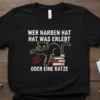 Black t-shirt with white German text "Wer Narben Hat Hat Was Erlebt Oder Eine Katze" and a black cat sitting