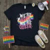 Black t-shirt with "We're Here We're Queer" text in pink and white, featuring a rainbow graphic and silhouettes of people