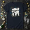 Navy t-shirt with white bold text "WHAT YEAR IS IT?" surrounded by gold and blue fireworks and confetti graphic