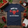 When Life Gives You Strawberry T-Shirt with a cartoon strawberry lifting a barbell, white text, navy blue shirt