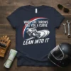 When Life Throws You A Curve Lean Into It text on a navy t-shirt with a graphic of a motorcycle