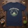 Navy t-shirt with "wholesome" text above a circular design of a cozy house, moon, stars, and floral wreath