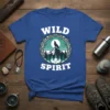 Wild Spirit t-shirt with a wolf howling on a mountain peak under the moon, surrounded by trees and nature elements