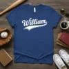 Blue t-shirt with "William" in white retro script font and a swoosh graphic below