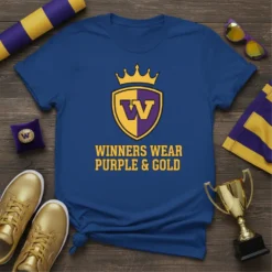 Blue t-shirt with "WINNERS WEAR PURPLE & GOLD" text and a shield logo with a crown, in purple and gold
