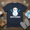 WINTER WONDER text with a cute cartoon snowman graphic on a navy t-shirt, surrounded by sparkles