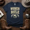 Navy t-shirt with "Women Rule" text in distressed cream font, featuring a circular emblem with a cowgirl on a horse