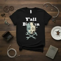 Black t-shirt with white text "Y'all Broken" above a cracked doll's head with buttons for eyes, crossed with a hammer