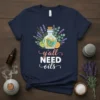 Navy t-shirt with "y'all NEED oils" text and a central graphic of a glass bottle filled with swirling oils, surrounded