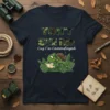 T-shirt design with camouflage text "YON'T SEE ME Cuz I'm Camouflaged" and a green chameleon wearing a backpack, holding a