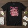 Black t-shirt with pink floral design and banner reading "You are Loved Enough Capable Strong" in white text