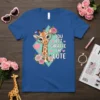 Giraffe wearing heart-shaped glasses and pearls with "You Bet Giraffe I'm Cute" text on a royal blue t-shirt