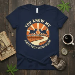 Navy t-shirt with "You Know Me Always Pussyfooting Around" text and two cats walking on a brick path, vintage sunburst