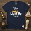 You Light Up my life quote with lighthouse graphic on navy blue t-shirt