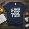 Navy t-shirt with white text saying "you look FUNNY with your HEAD TURNED like that" and a cartoon head illustration