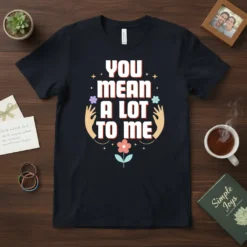 T-shirt with white bold text "YOU MEAN A LOT TO ME" surrounded by floral graphics and hands