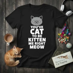 Black t-shirt with "YOU'VE CAT TO BE KITTEN ME RIGHT MEOW" in white text and a grumpy cat graphic