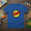 Blue t-shirt with bold red "ZAP!" text in a comic book explosion graphic, featuring a yellow circle and blue starburst
