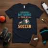"I Pause My Game To Play Soccer" text design with a soccer ball in motion on a navy t-shirt