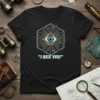 "I SEE YOU" text with a cybernetic eye graphic on a black t-shirt, designed for tech and conspiracy enthusiasts