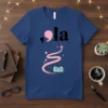 Blue ,ola literary quote t-shirt with a pink comma and 'la' text above an open book, pink swirl, and stars
