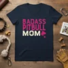 Badass Pitbull Mom text in distressed pink and cream, with a pitbull silhouette and paw print on a navy v-neck