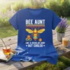 Bee Aunt Like A Regular Aunt But Cooler quote on a blue t-shirt with a colorful bee graphic and honeycomb