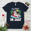 Christmas In July t-shirt with a polar bear wearing a Santa hat and sunglasses, relaxing on a float in the
