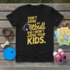 Black t-shirt with yellow text: "Don't Judge My Pitbull And I Won't Judge Your Kids." Features a white pitbull graphic