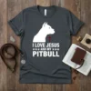 White text "I LOVE JESUS AND MY PITBULL" with paw prints and a pitbull silhouette on a dark heather t-shirt