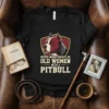 Never Underteimate An Old Women With A Pitbull quote on a black t-shirt, featuring a pitbull head graphic inside a
