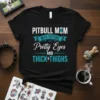 Pitbull mom t-shirt with text "Pitbull Mom With Tattoos Pretty Eyes And Thick Thighs" and a paw print graphic