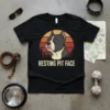 Black t-shirt featuring a pitbull portrait with the text "RESTING PIT FACE" below, set against a retro sunset graphic