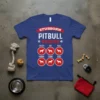 Blue t-shirt with "Stubborn Pitbull Tricks" text and icons of pitbulls performing tricks like catch, sit, roll, shake, come, and